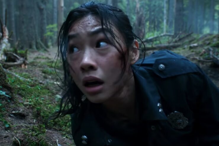 A woman lies on the ground in the forest looking very alarmed in Hope