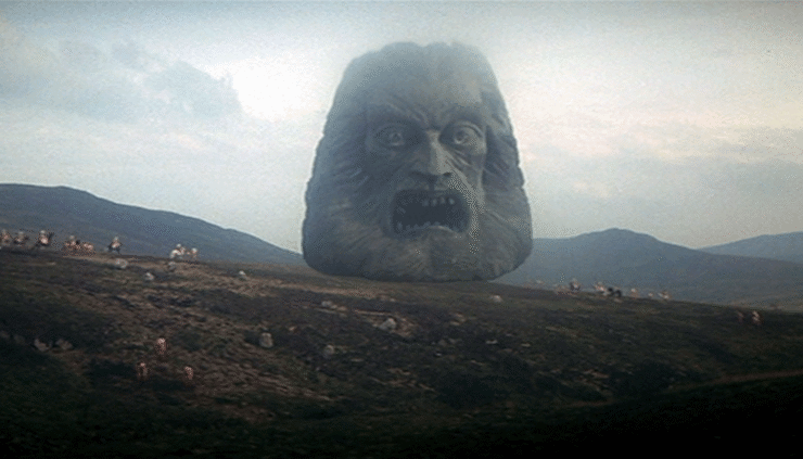 Screenshot from Zardoz (1974): a giant stone head of Zardoz floats above a landscape